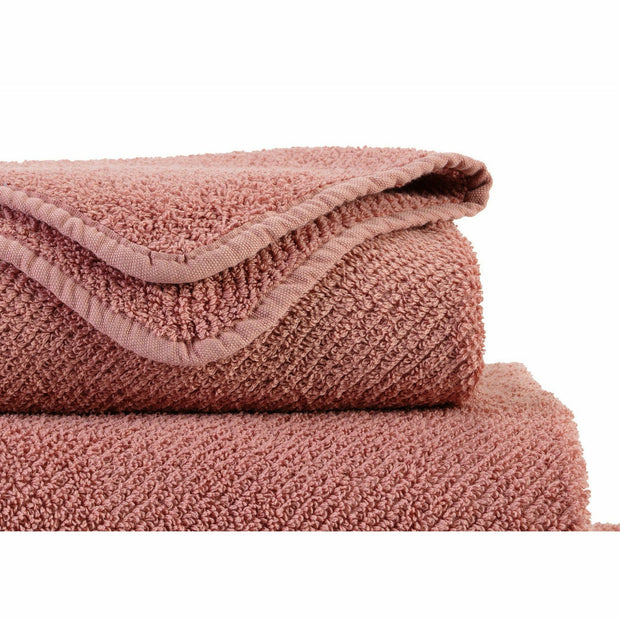 Two pink towels stacked on a white background