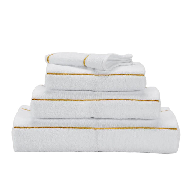 Stack of white towels with gold trim on a light gray background